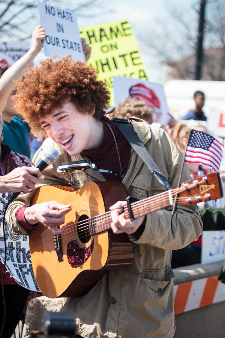 Battle of the bands: the protesters against Trump featured a young musician singing classics by Bob Dylan, Woody Guthrie, and Peter, Paul And Mary.