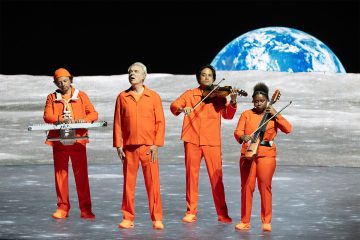 David Byrne and band in front of a moon backdrop